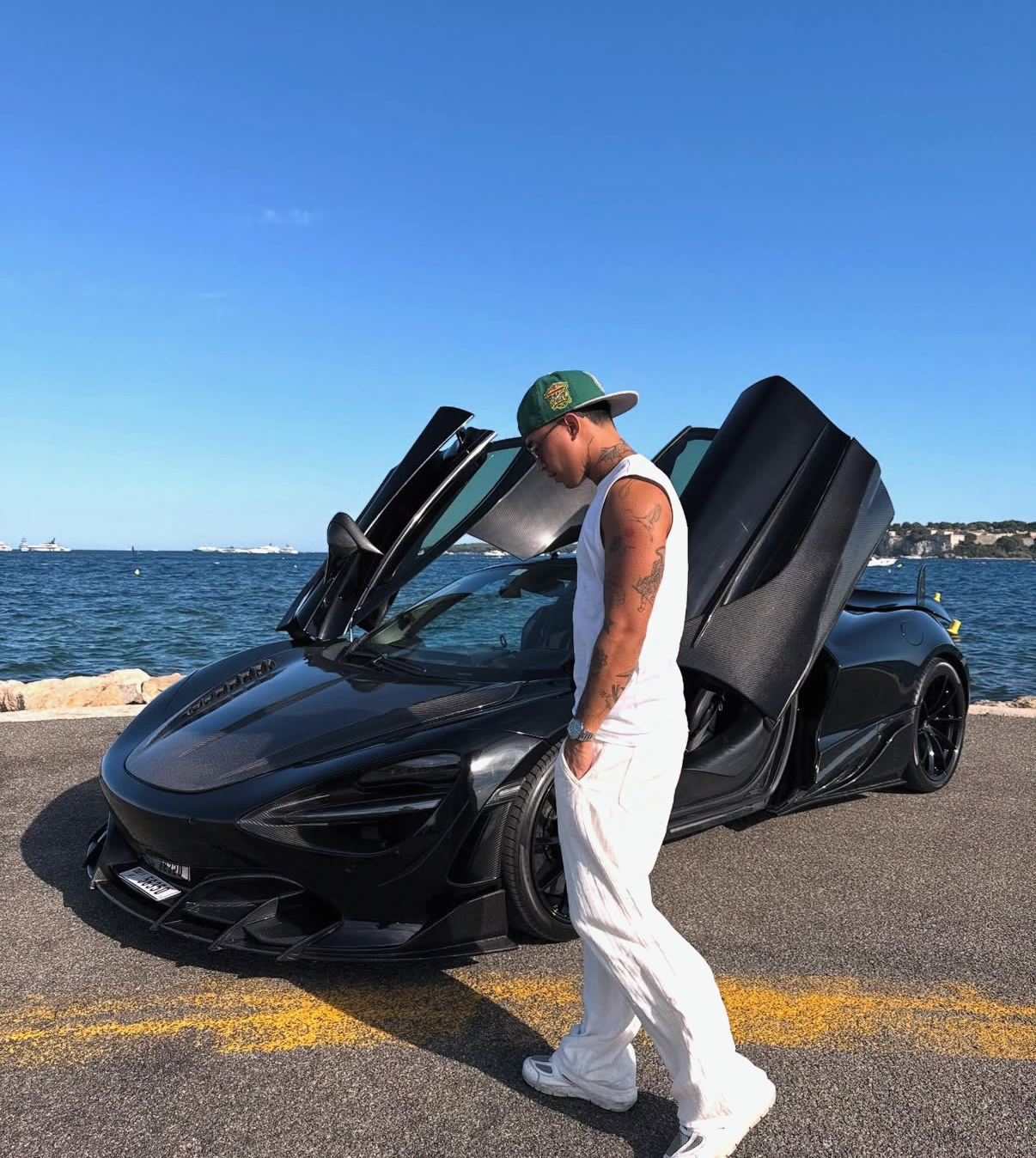 Homme debout devant une supercar noire aux portes ouvertes sur une route côtière, symbole de réussite, de liberté et de succès digital avec Sirius Circle.